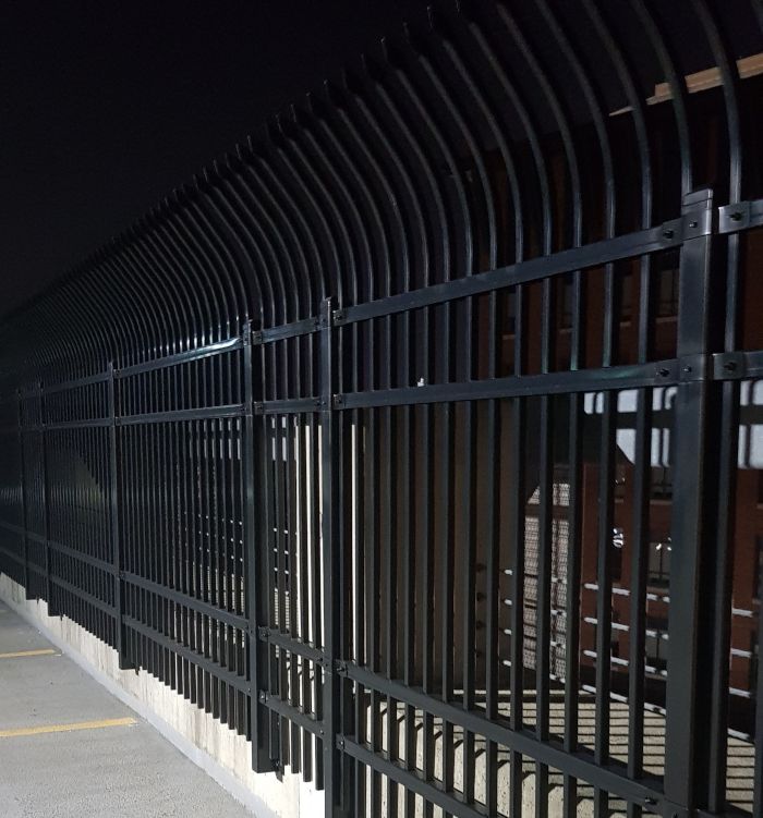 a steep metal bar fence with inward curved edges encasing the roof floor of a parking garage