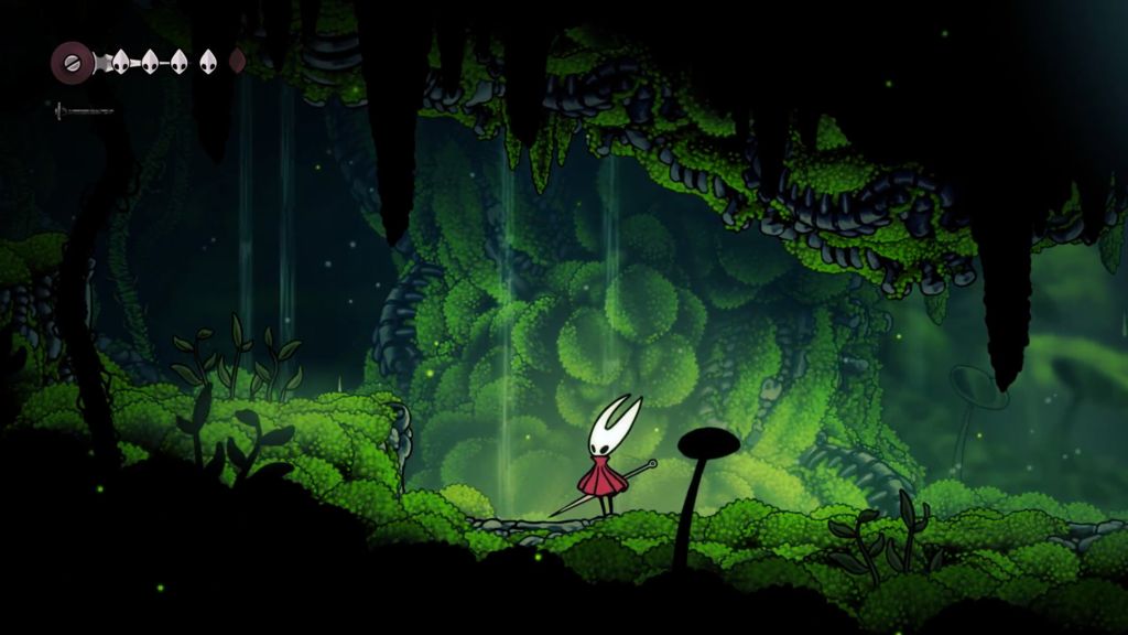 A cave tunnel overgrown with bright green moss and leafy plants. Moss has covered most stalactites